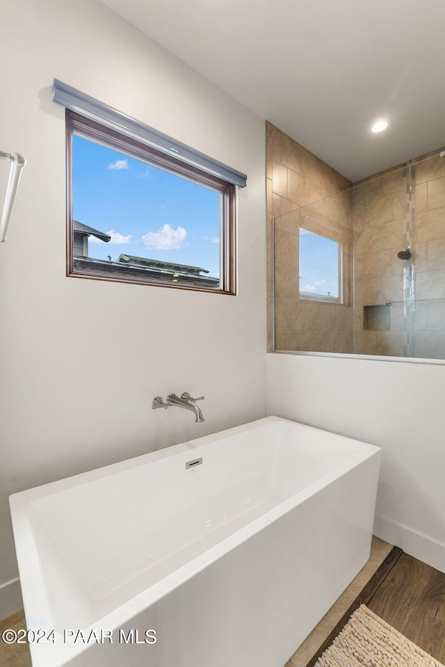 bathroom with hardwood / wood-style floors and shower with separate bathtub