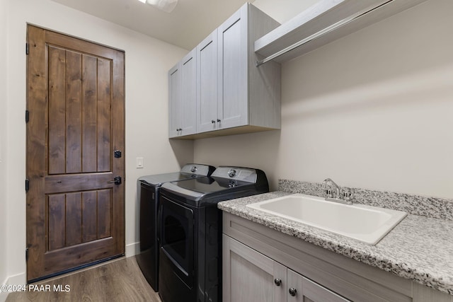 laundry room featuring washer and clothes dryer, sink, cabinets, and dark hardwood / wood-style floors