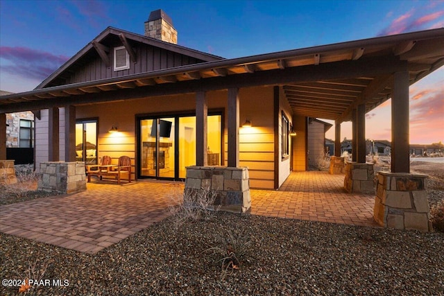 back house at dusk featuring a patio