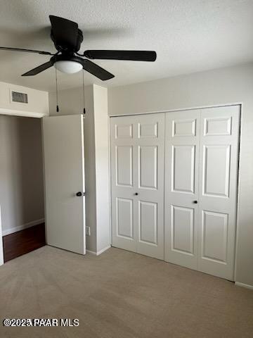 unfurnished bedroom with a textured ceiling, light hardwood / wood-style flooring, a closet, and ceiling fan