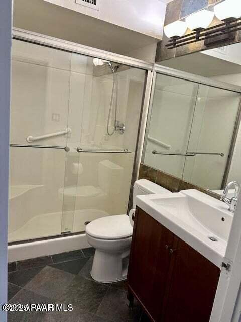 bathroom featuring a shower with door, vanity, tile patterned flooring, and toilet