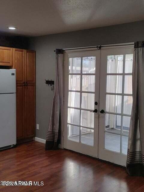 doorway to outside with french doors, dark wood-type flooring, and a textured ceiling