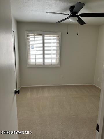 unfurnished room featuring ceiling fan, light carpet, and a textured ceiling