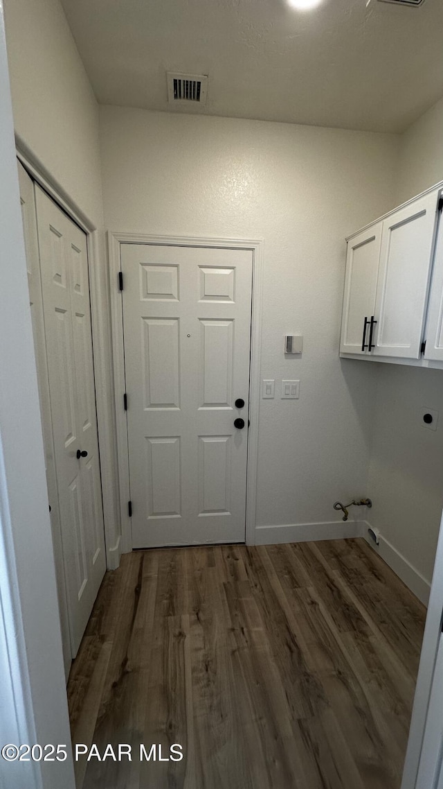 clothes washing area featuring gas dryer hookup, dark hardwood / wood-style flooring, and cabinets