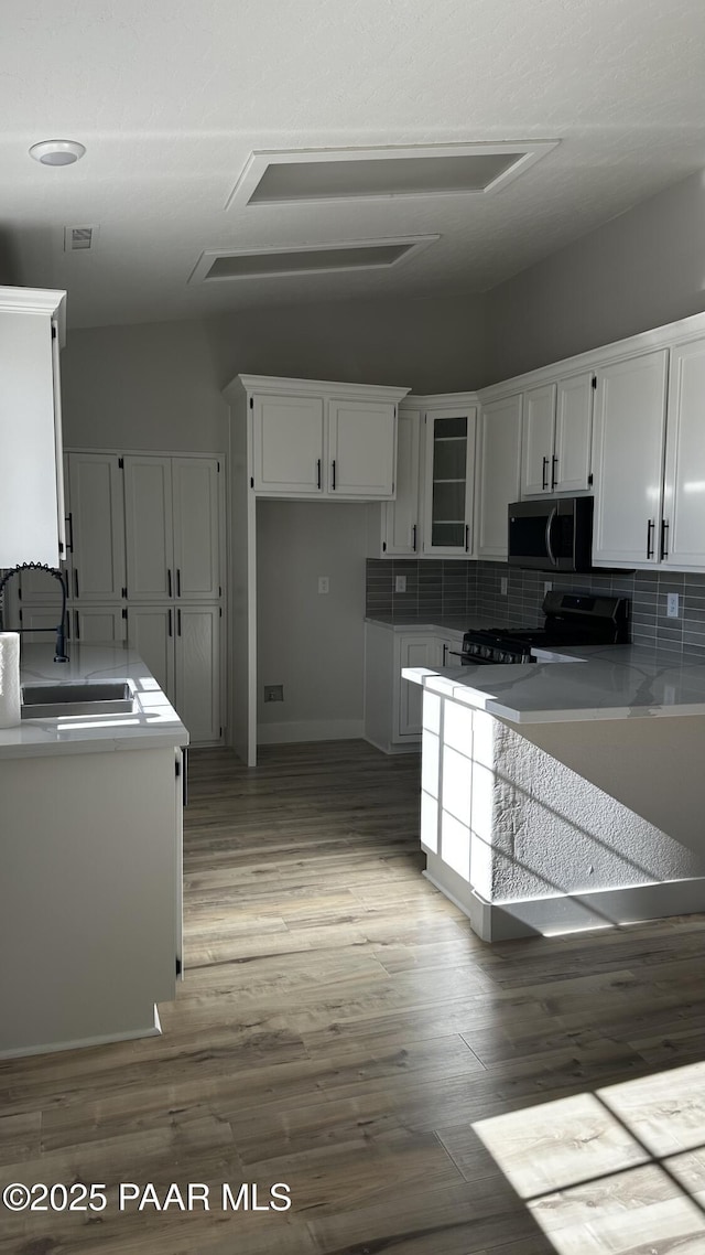 kitchen featuring sink, white cabinets, wood-type flooring, decorative backsplash, and electric range