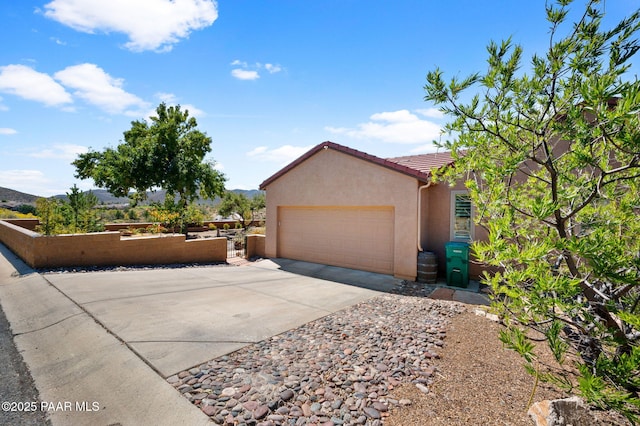 view of property exterior featuring a tile roof, an attached garage, driveway, and stucco siding