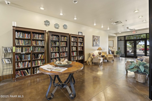 interior space with visible vents, recessed lighting, concrete flooring, and wall of books