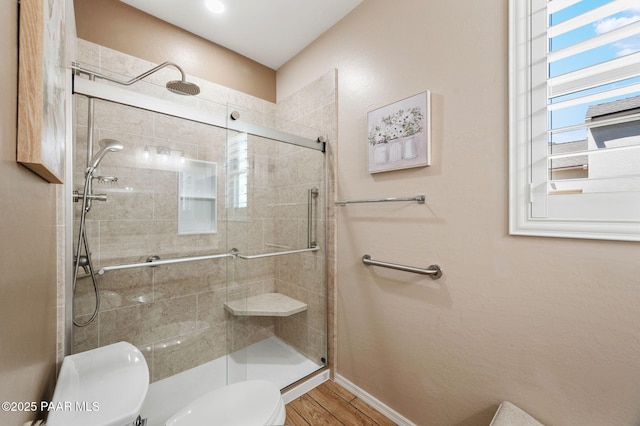 full bathroom featuring a shower stall, toilet, wood finished floors, and baseboards