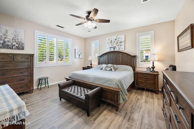 bedroom featuring visible vents, multiple windows, baseboards, and wood tiled floor