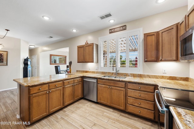 kitchen with visible vents, appliances with stainless steel finishes, a peninsula, brown cabinetry, and a sink