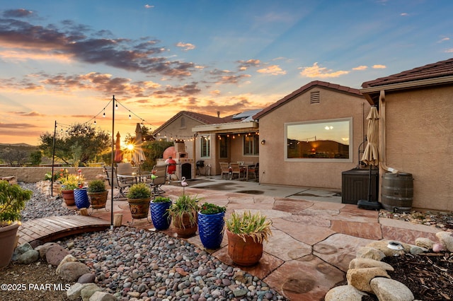 rear view of property with a patio, solar panels, outdoor dining area, stucco siding, and a tiled roof