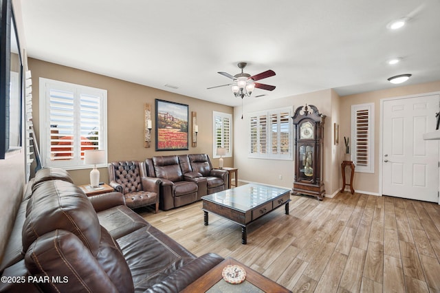 living area with plenty of natural light, a ceiling fan, and light wood finished floors