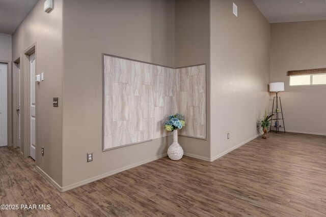 interior space with a high ceiling, wood finished floors, and baseboards