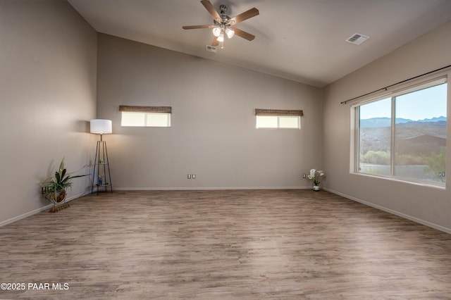 spare room with visible vents, lofted ceiling, baseboards, and wood finished floors