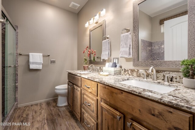 full bathroom with a sink, visible vents, toilet, and wood finished floors