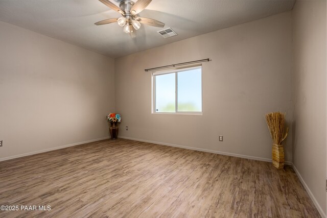 spare room featuring visible vents, ceiling fan, baseboards, and wood finished floors