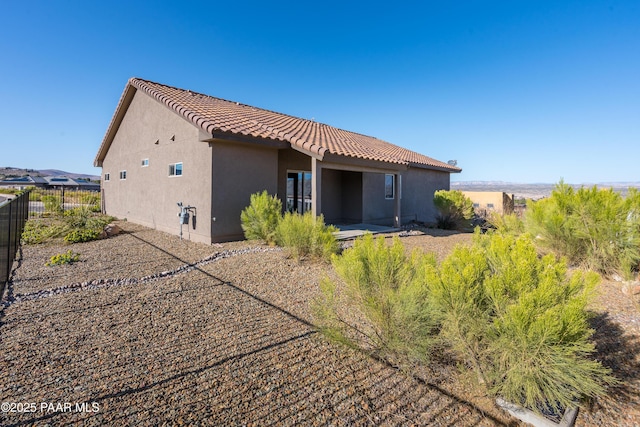 back of property featuring a tiled roof, fence, and stucco siding