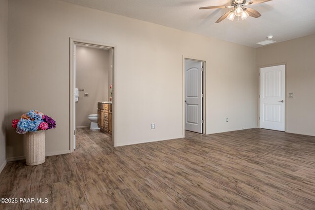 unfurnished bedroom featuring ensuite bath and wood finished floors