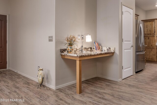 interior space with built in desk, baseboards, and wood finished floors