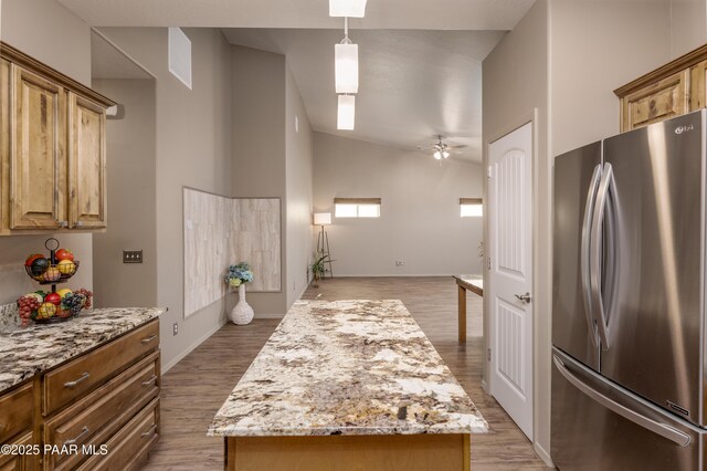 kitchen featuring light stone counters, light wood-type flooring, freestanding refrigerator, and a ceiling fan