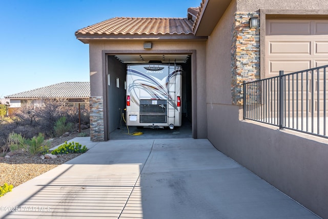 property entrance with driveway, an attached garage, stucco siding, stone siding, and a tiled roof