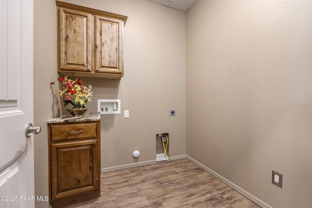 washroom featuring electric dryer hookup, washer hookup, light wood-style flooring, cabinet space, and baseboards