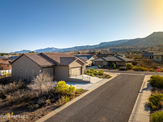 view of front of house with a residential view, stucco siding, concrete driveway, a tile roof, and a mountain view