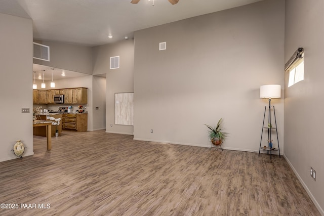 living area with visible vents, baseboards, a ceiling fan, and wood finished floors