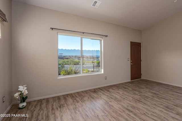 spare room featuring visible vents, baseboards, and wood finished floors