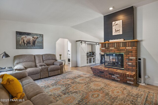 4361 N Covina Cir, Prescott Valley, AZ 86314 - living room with wood finished floors, arched walkways, vaulted ceiling, a brick fireplace, and baseboards