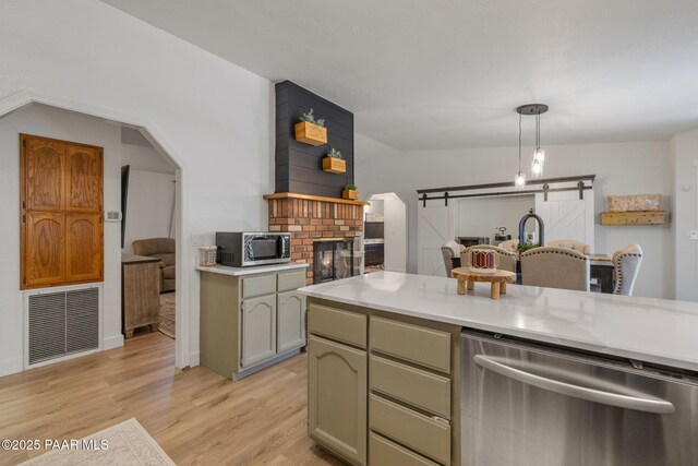 4361 N Covina Cir, Prescott Valley, AZ 86314 - kitchen featuring appliances with stainless steel finishes, light countertops, light wood-style floors, a fireplace, and a barn door