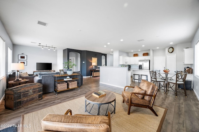 living room with dark hardwood / wood-style flooring and track lighting