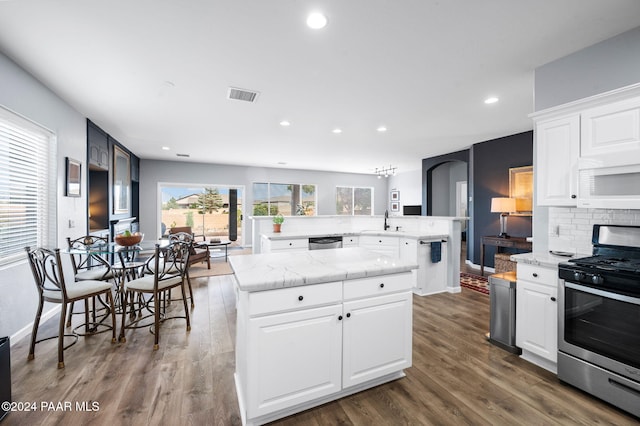 kitchen with appliances with stainless steel finishes, a center island, white cabinetry, and dark hardwood / wood-style flooring