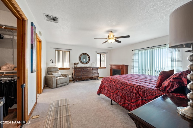 bedroom featuring ceiling fan, light colored carpet, and a textured ceiling