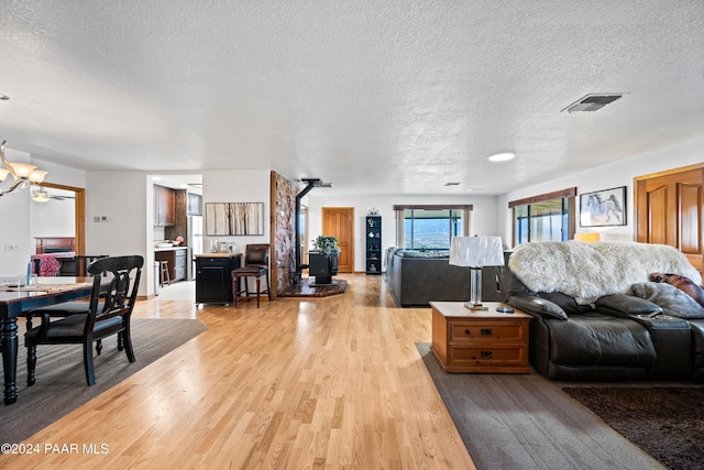 living room featuring a wood stove, a textured ceiling, and light wood-type flooring