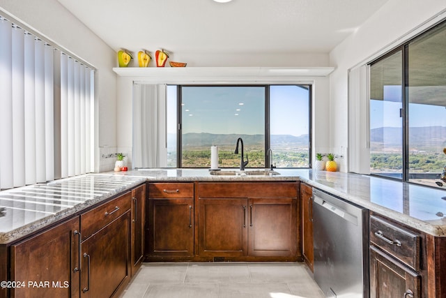 kitchen with light stone countertops, a mountain view, sink, light tile patterned floors, and dishwasher