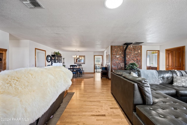 bedroom featuring a notable chandelier, a textured ceiling, and light wood-type flooring