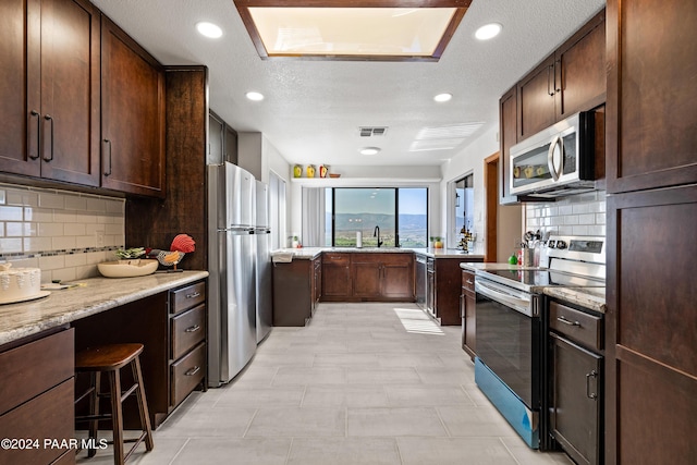 kitchen with decorative backsplash, stainless steel appliances, and a textured ceiling