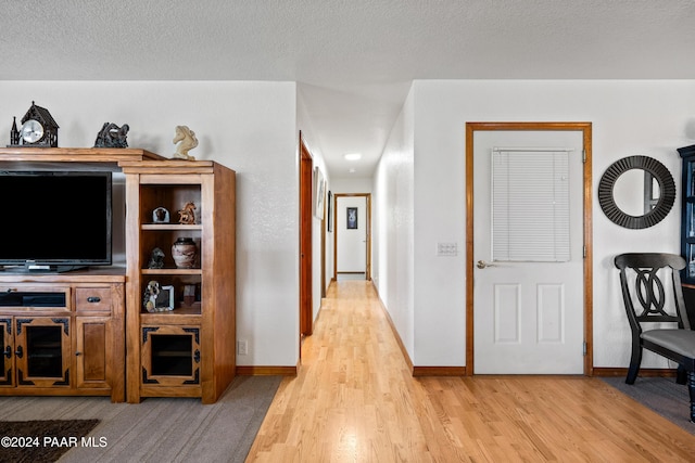 corridor featuring a textured ceiling and light hardwood / wood-style flooring