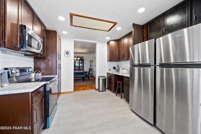 kitchen featuring light stone countertops, light hardwood / wood-style flooring, a textured ceiling, decorative backsplash, and appliances with stainless steel finishes