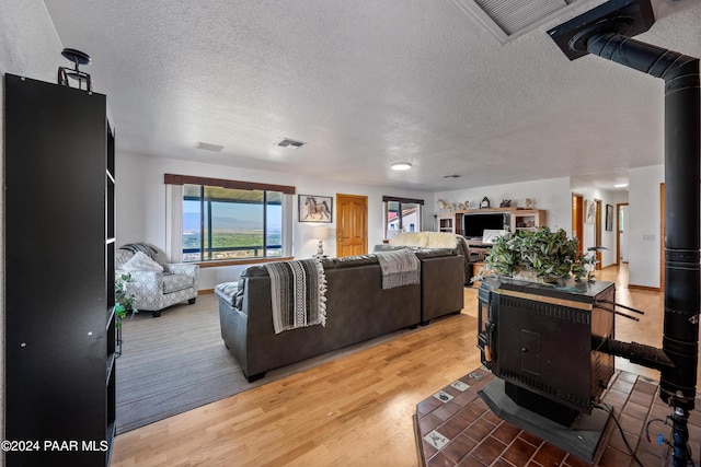 living room with a wood stove, wood-type flooring, and a textured ceiling