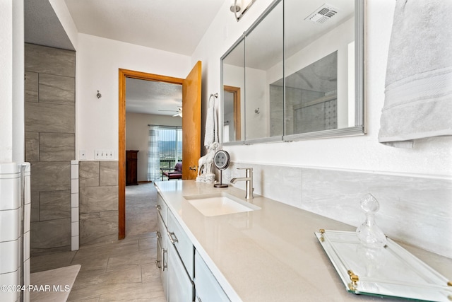 bathroom featuring ceiling fan, tile patterned flooring, vanity, and tile walls