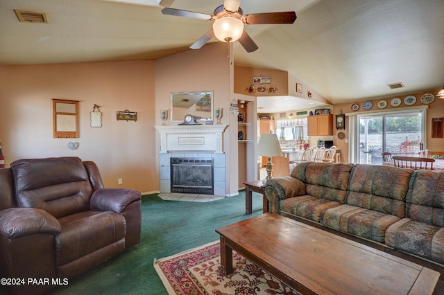 carpeted living room with vaulted ceiling, ceiling fan, and a tiled fireplace