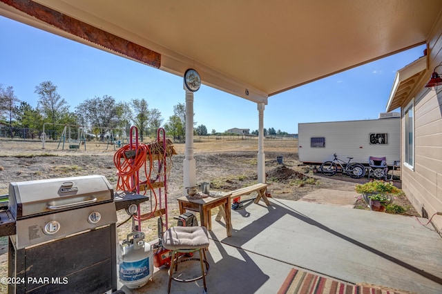 view of patio / terrace featuring a playground, a grill, and a rural view