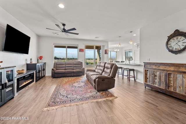 living room with light wood-type flooring, ceiling fan, and sink