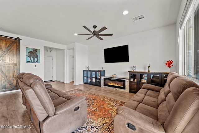 living room with wood-type flooring, a barn door, and ceiling fan