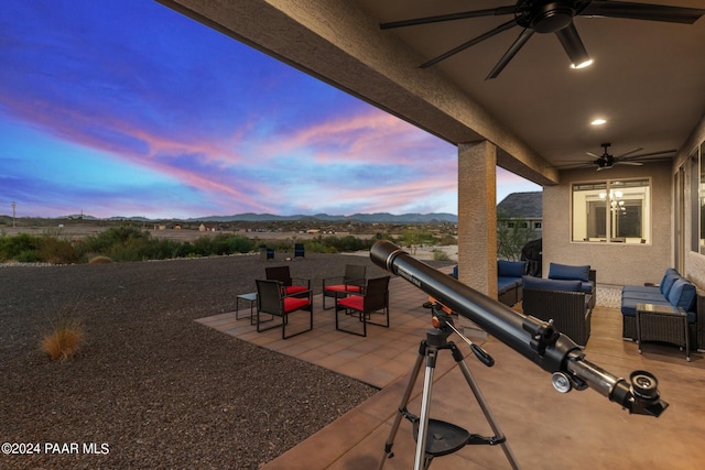 patio terrace at dusk featuring a mountain view, an outdoor hangout area, and ceiling fan