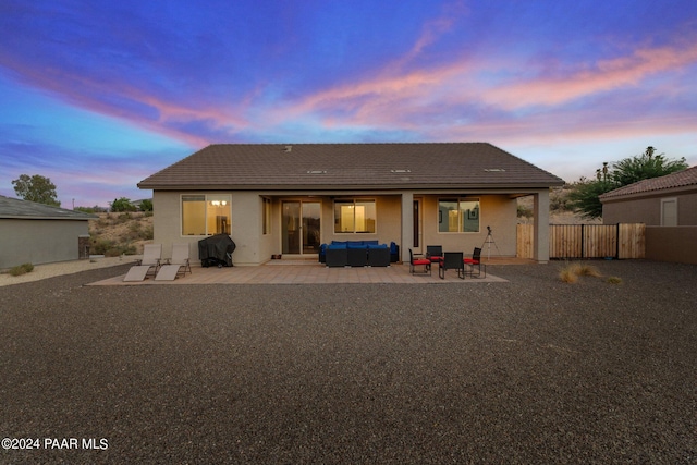 back house at dusk featuring an outdoor living space and a patio area