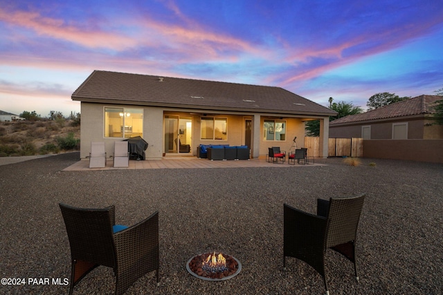 back house at dusk with a patio and an outdoor living space with a fire pit