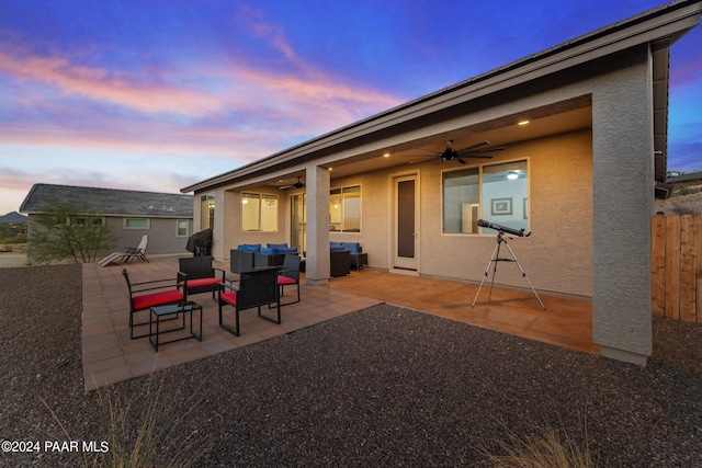 back house at dusk featuring outdoor lounge area, ceiling fan, and a patio area